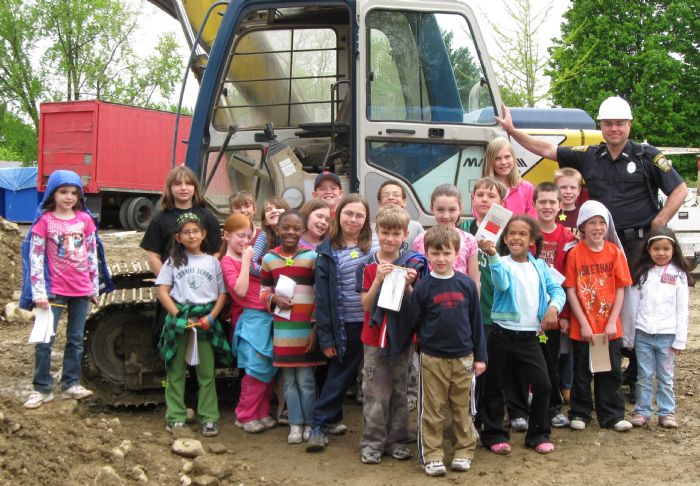 Reporters from the Cunniff Kids News and Officer Lloyd Burke (second from right, with hard hat) pose near one of the many machines at the site of the new Watertown police station in May 2009. At the time, the station was scheduled to open in Spring 2010.
