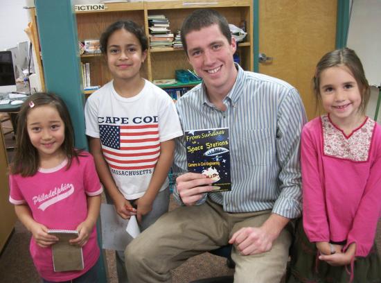 John Quinn (seated) takes a moment from checking in a new library book to pose
with reporters from the Cunniff Kids News